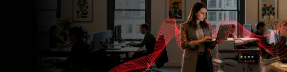 Woman typing on a laptop next to a Sharp MFP 