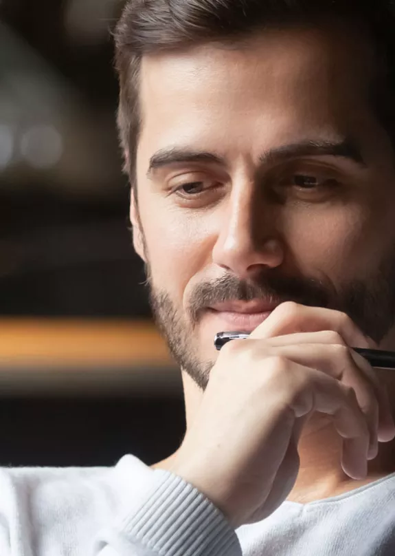 A man holding a pen whilst using a laptop