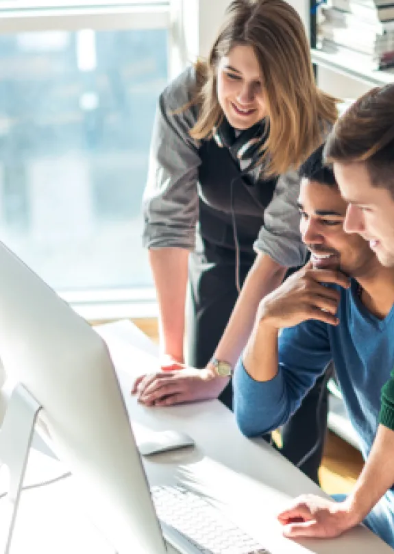 Three colleagues looking at PC screen