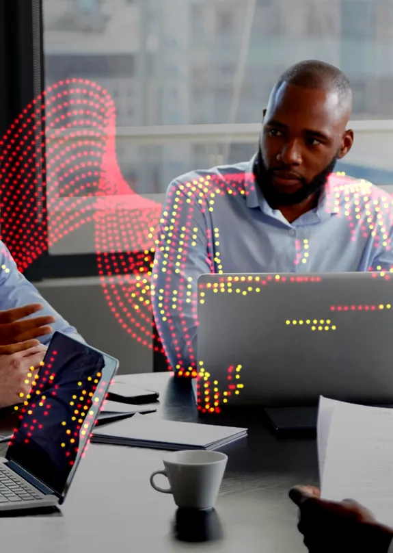 Group of people having a team meeting around a table with laptops in front of them 